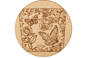 Eine runde Holzgravur zeigt Schmetterlinge, Rosen und geschwungene Blütenranken in feinen Linien.